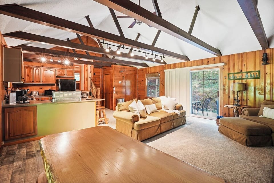 This inviting open space features cozy sofas, vaulted wood beam ceilings, and a warm kitchen with bar seating. Sliding doors bring in natural light, making it the perfect spot to cook, dine, and relax together in comfort.