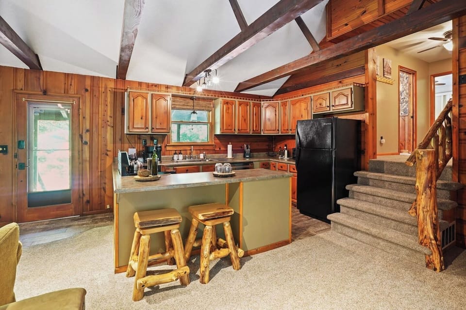Enjoy cooking in this rustic kitchen with wood cabinetry, vaulted ceilings, and a spacious island with log-style stools. Warm and inviting, it’s the perfect spot to gather for meals, snacks, or a glass of wine after a day of exploring.