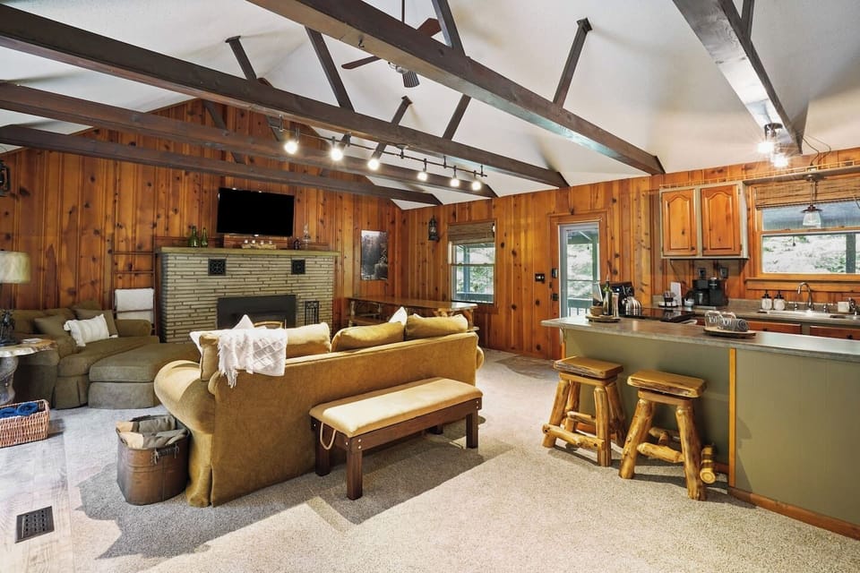 Enjoy the open-concept living area featuring vaulted ceilings, a wood-burning fireplace, and a fully equipped kitchen with bar seating, perfect for cooking, dining, and relaxing together after exploring the beauty of the surrounding area.