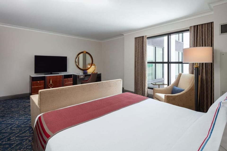 Unwind in a plush bed with TV and lounge chair.