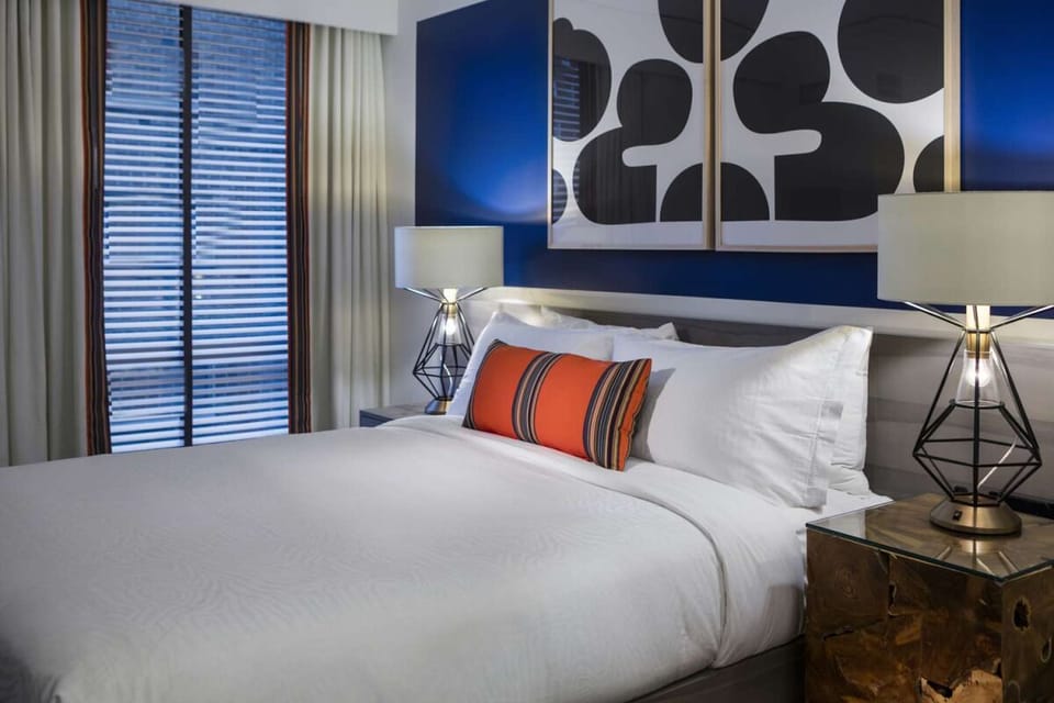 Sink into crisp linens beneath warm lamps and bold artwork.