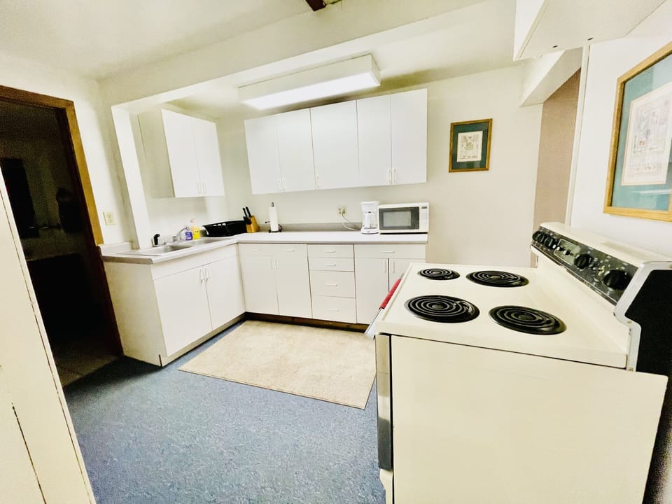 Kitchen with stove, coffee maker, microwave, and popcorn popper. 