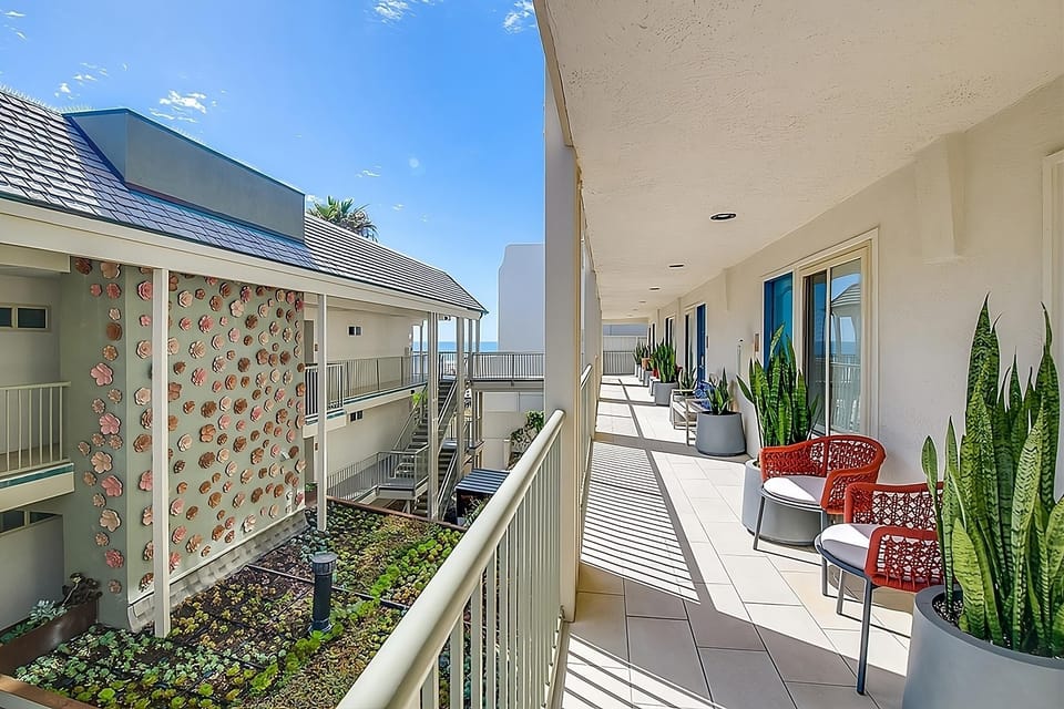 Stroll sunlit open-air corridors framed by coastal greenery.
