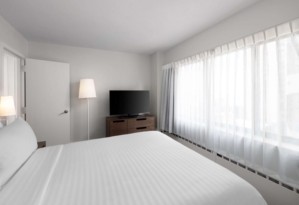 Wake refreshed in a calm room with oversized windows.