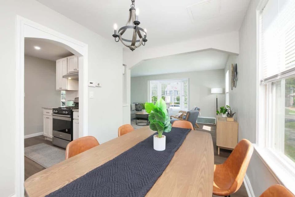 - Dining area with chandelier and greenery centerpiece design   - Open flow connects kitchen to living space for easy hosting   - Large window brightens meals with plenty of natural light  