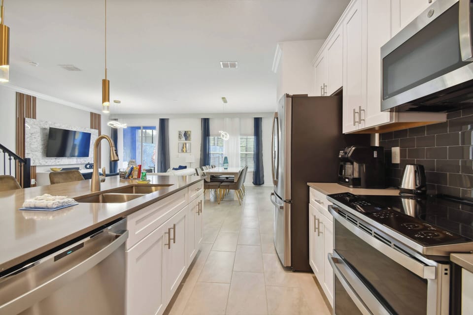 Discover a stylish kitchen with sleek stainless steel appliances and a beautiful island ideal for meal prep or casual dining. Warm wood cabinetry and a vibrant tile backsplash create a welcoming space filled with natural light.