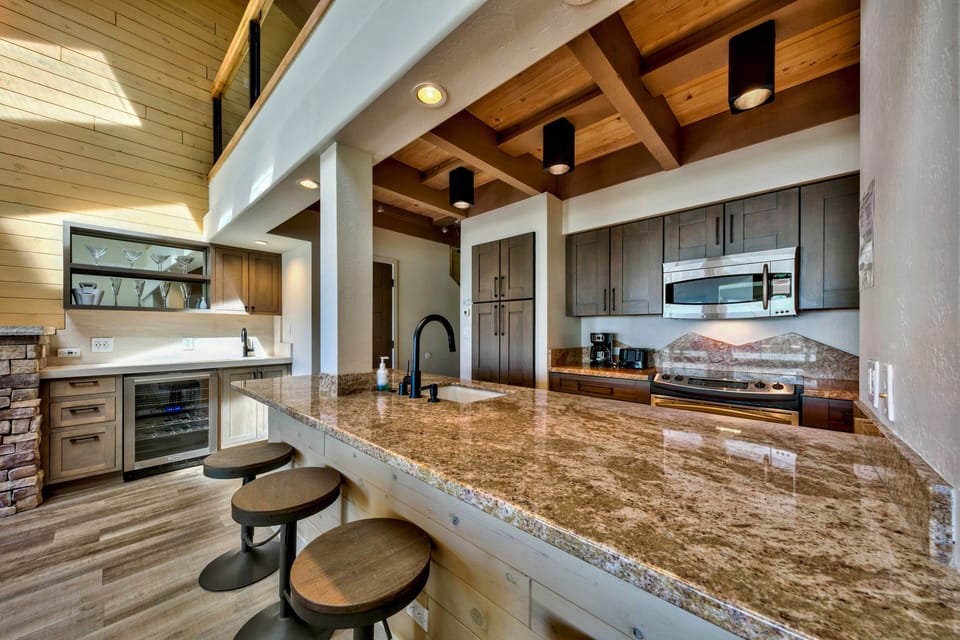 You'll love preparing meals in this stunning open-concept kitchen featuring granite countertops, modern appliances, and elegant exposed beam ceiling.
