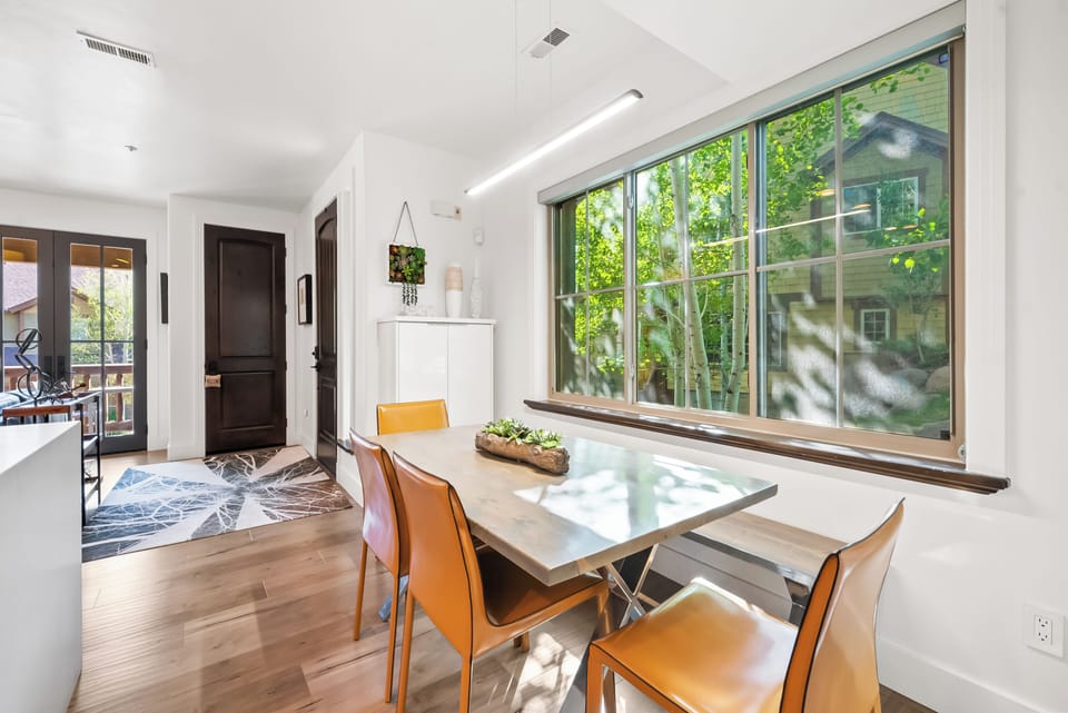 - Dine together at a modern table with sleek seating  
- Large window view of greenery enhances mealtime  
- Open layout connects dining space to the kitchen