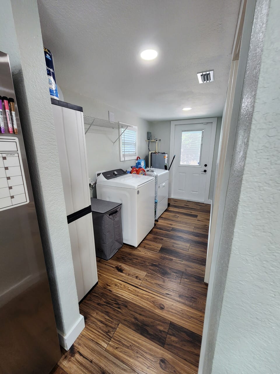 Hallway laundry with washer, dryer, hamper, and shelving to keep clothes organiz