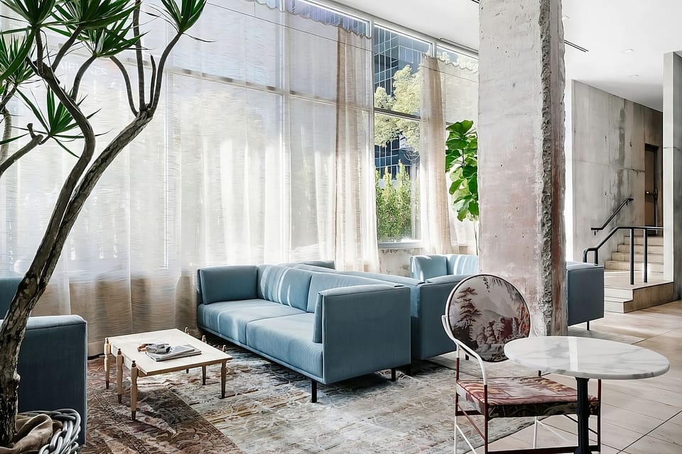 Relax on plush sofas beside towering windows and greenery.