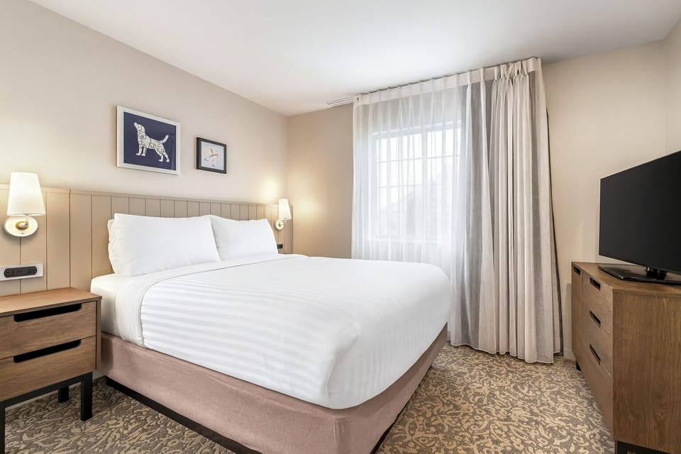 Unwind in crisp linens beside soft light and quiet views.