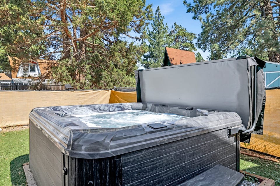 Spacious backyard with a relaxing hot tub, BBQ, outdoor dining area, comfy seating, perfect for peaceful evenings outdoors.
