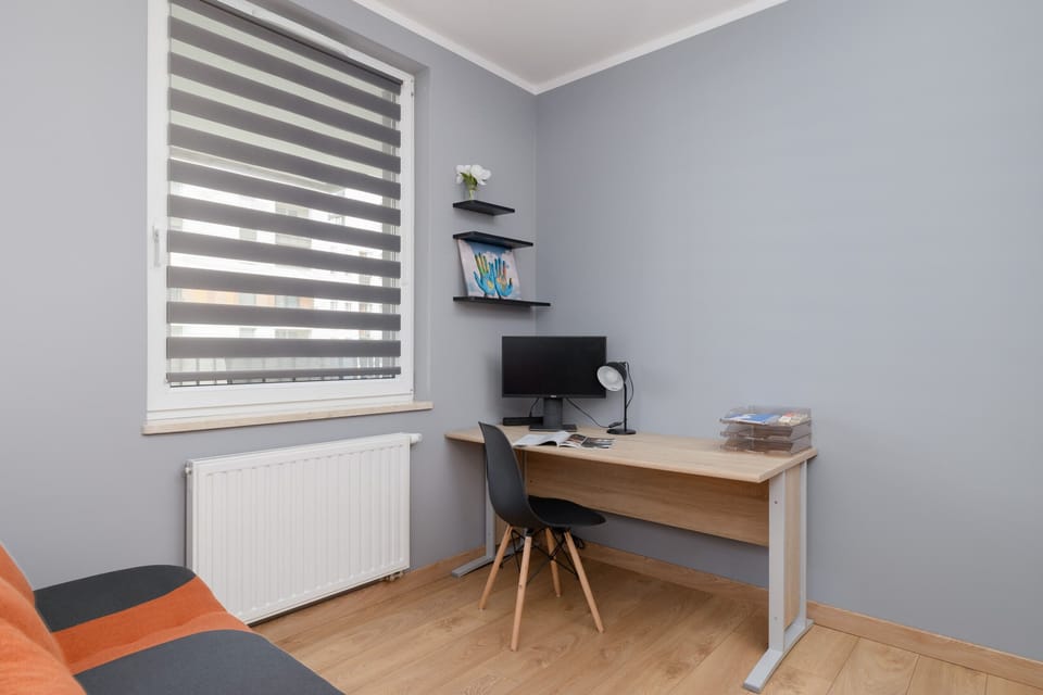 A functional workspace setup with a desk, shelves, and a stylish lamp, perfect for remote work.


