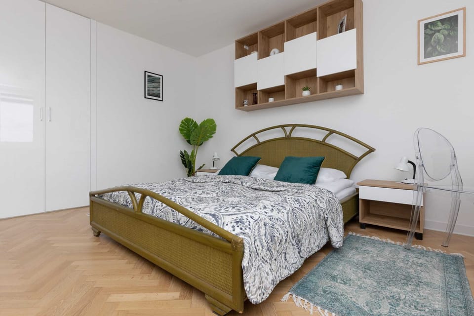 A close-up of the bedroom, featuring a comfortable bed, warm tones, and floating wooden shelves.


