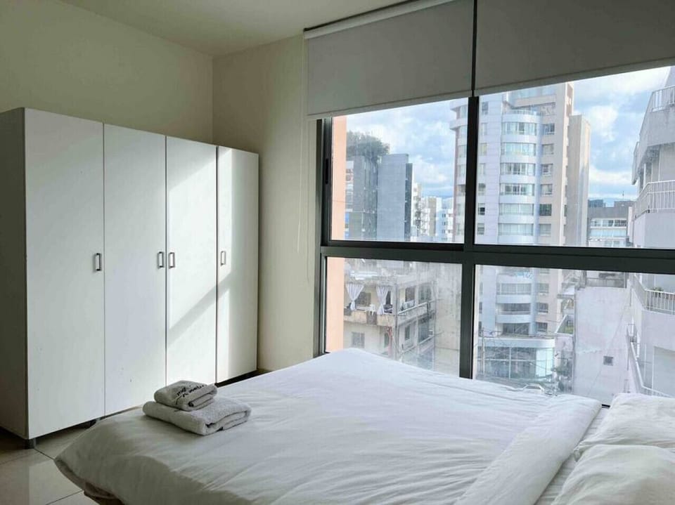 Well-lit guest room equipped with ample storage space and a scenic city backdrop.