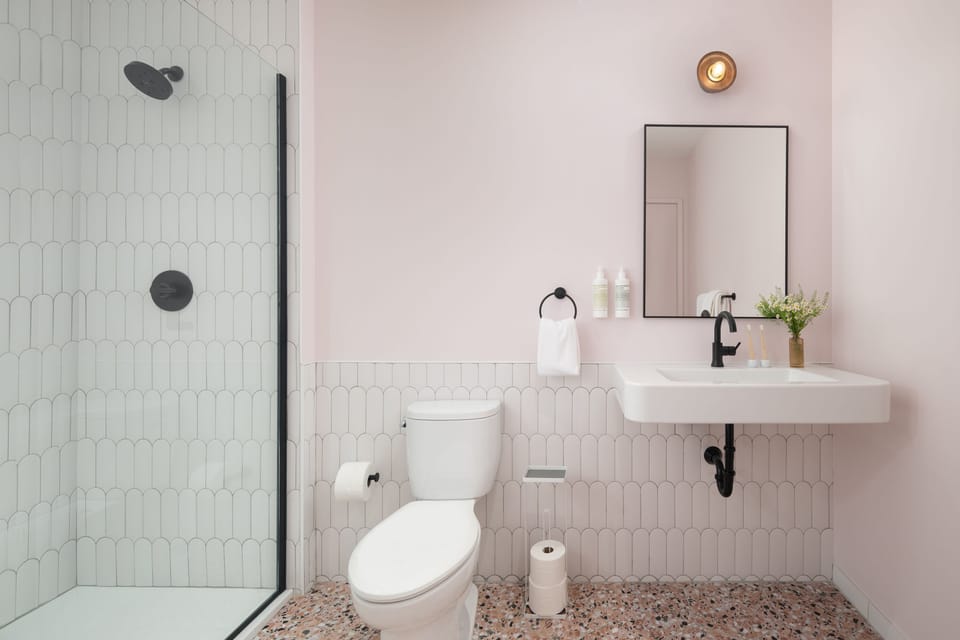 Premium Sferra Towels, Malin + Goetz bath products, sink with mirror, walk-in shower. 