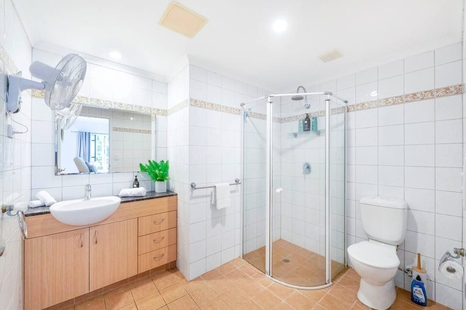 An immaculate en-suite bathroom with enclosed shower and fan.