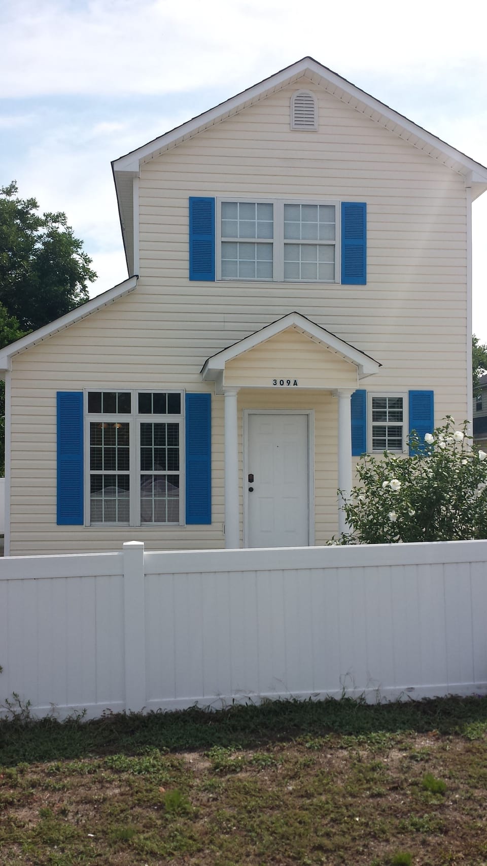 Front of the house adorned with beautiful greenery and a fully enclosed fence.