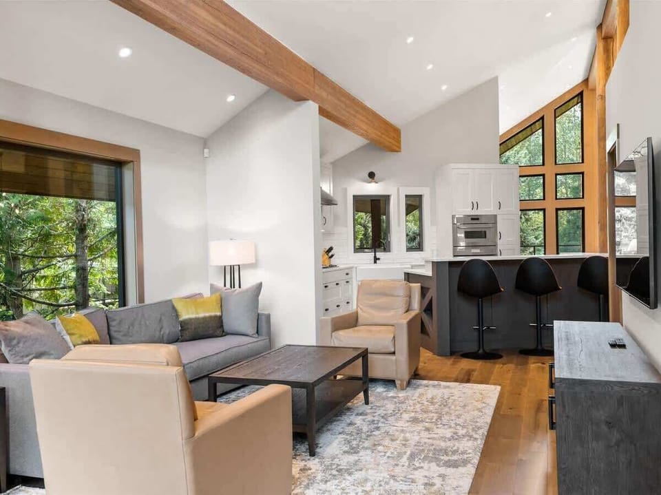 - Open-concept living room flowing into the sleek modern kitchen  
- Natural light fills the space with cozy seating and warm wood tones  
- Great setup for family gatherings and evening relaxation  