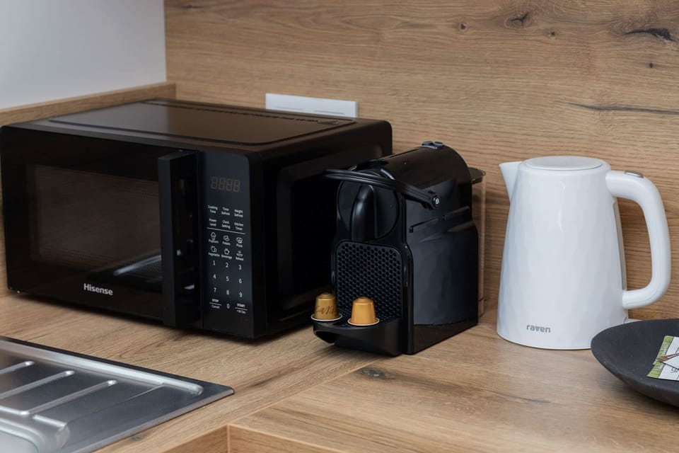 A close-up of small kitchen appliances including a microwave, kettle, and coffee machine.

