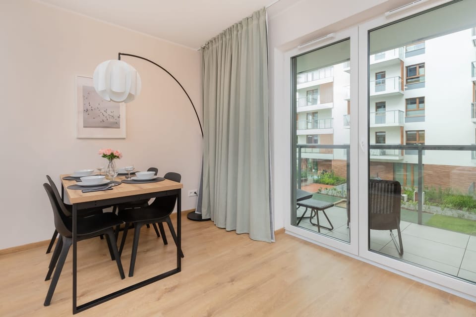 A dining area with a table set for four, located near large sliding glass doors leading to the balcony.

