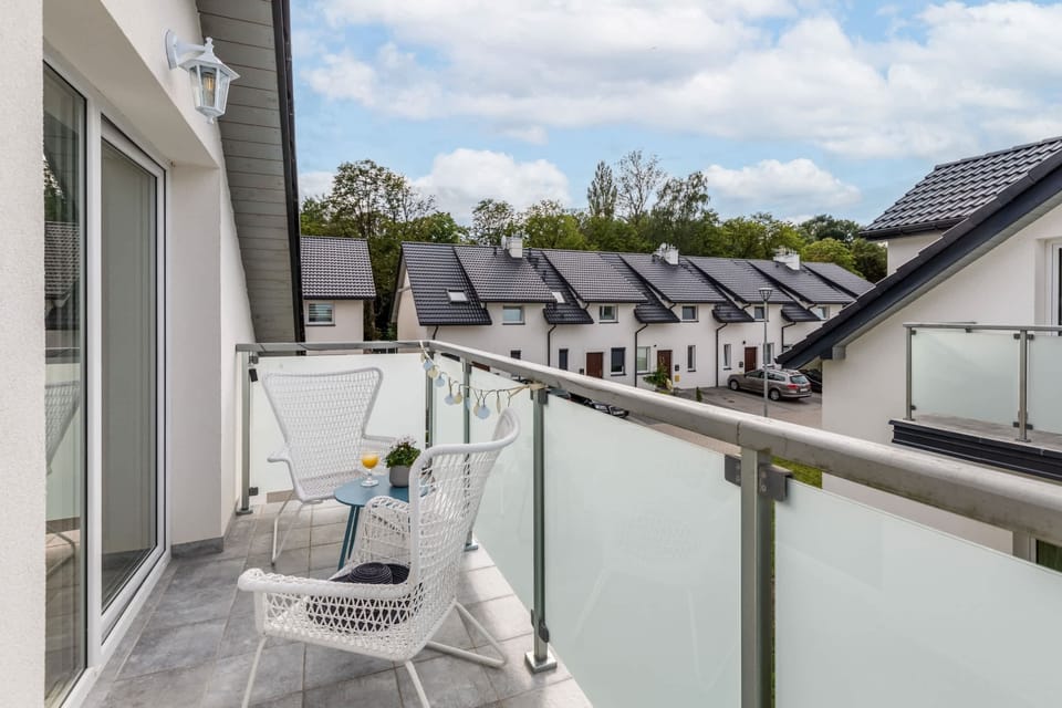 A balcony with charming furniture, providing a view of rooftops and greenery.

