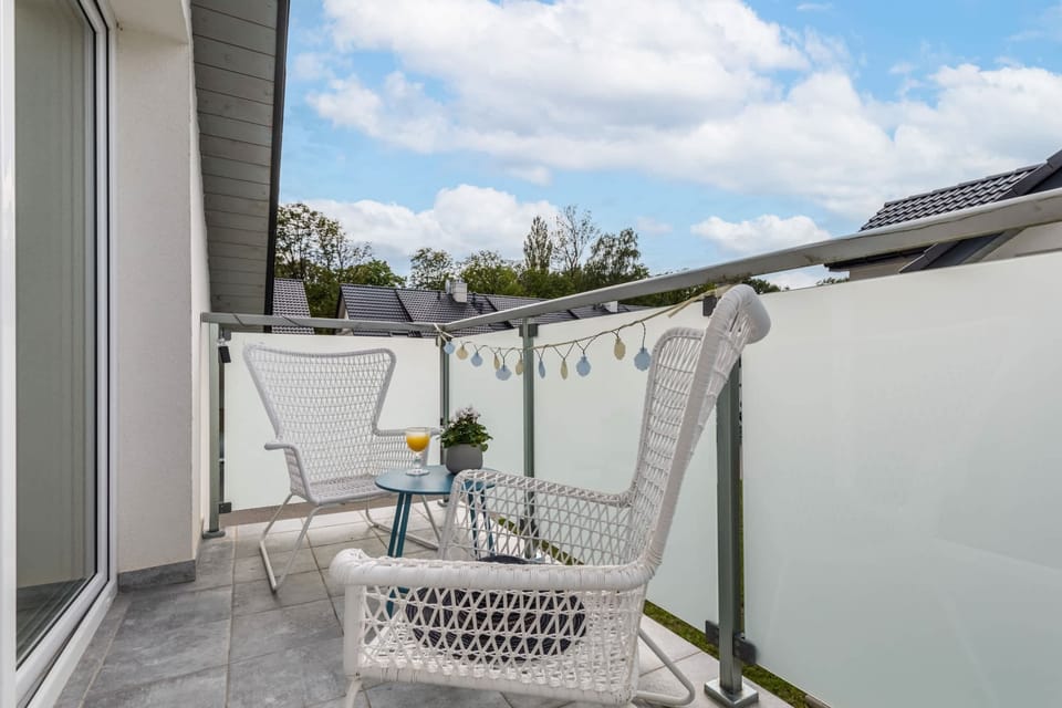 A charming balcony with a small table and chairs, offering a view of the rooftops.

