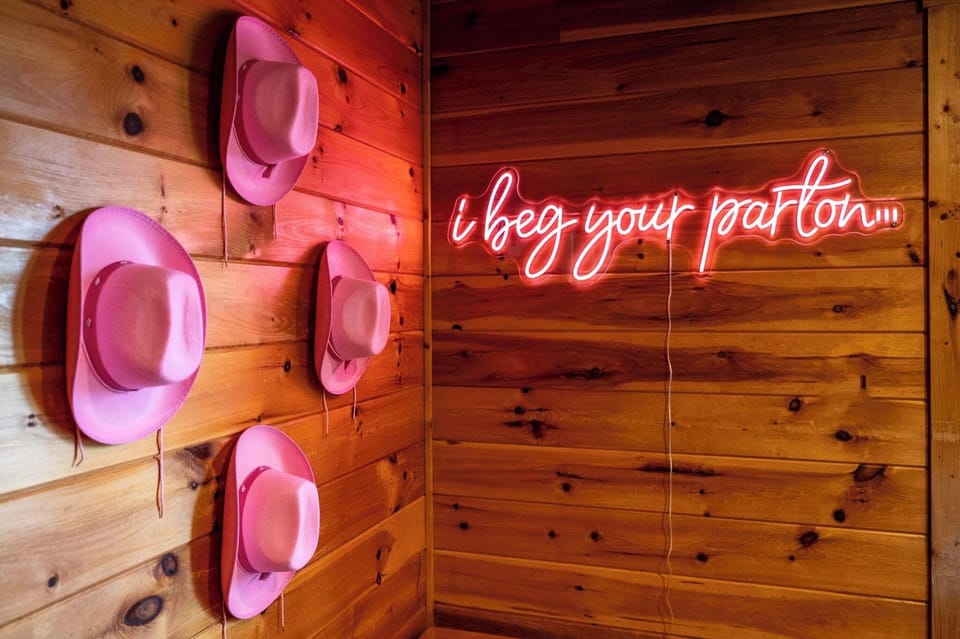 Selfie spot in front of our Dolly-themed neon sign and hat wall. Game room amenities include: NEW leather sleeper sofa, kitchenette, full fridge, tons of games and mountain views!