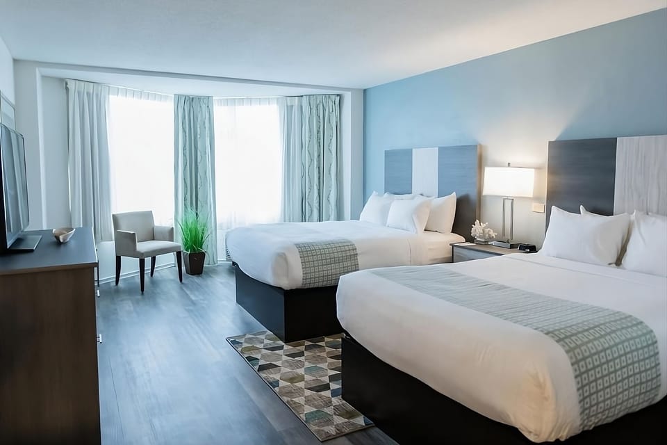 Settle into a calm, airy double-queen room with soft daylight.