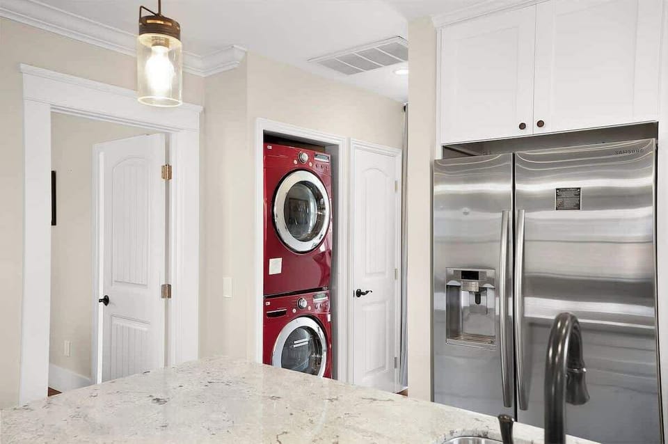 Stainless-steel kitchen with French-door fridge and peek-through to laundry—smart, functional layout