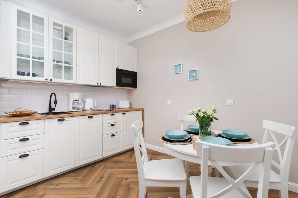 A modern kitchen with white cabinets, wooden countertops, and a dining table set for two.

