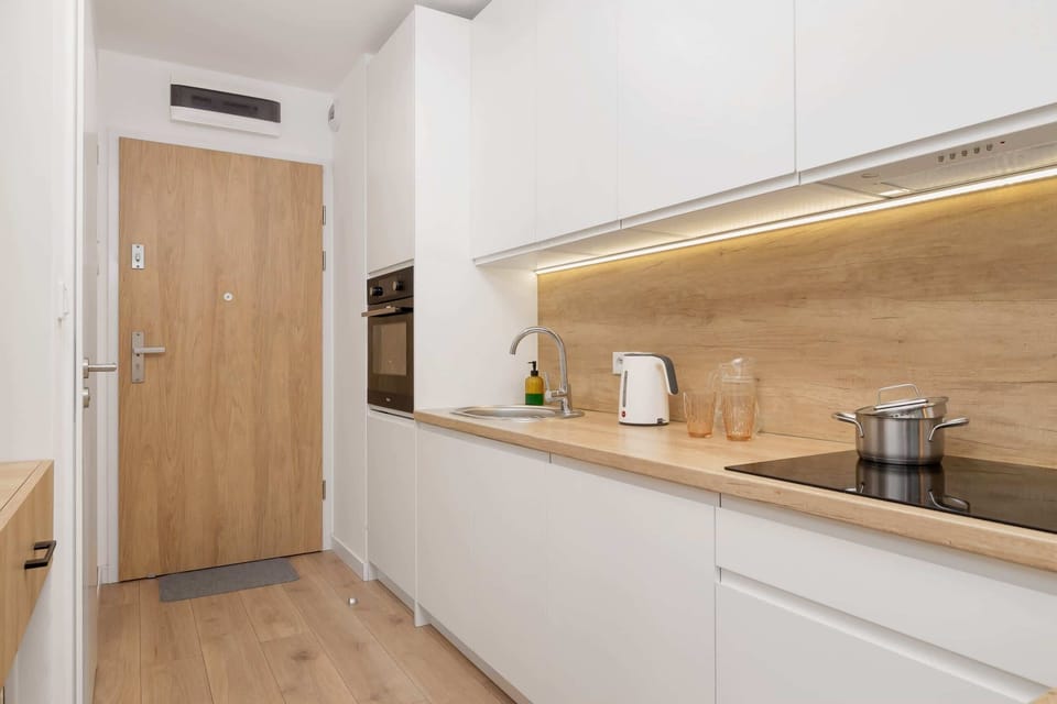 A full view of the kitchen with modern white cabinetry and wooden accents.

