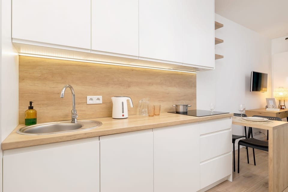A sleek kitchen with white cabinets, wooden countertops, and soft under-cabinet lighting.

