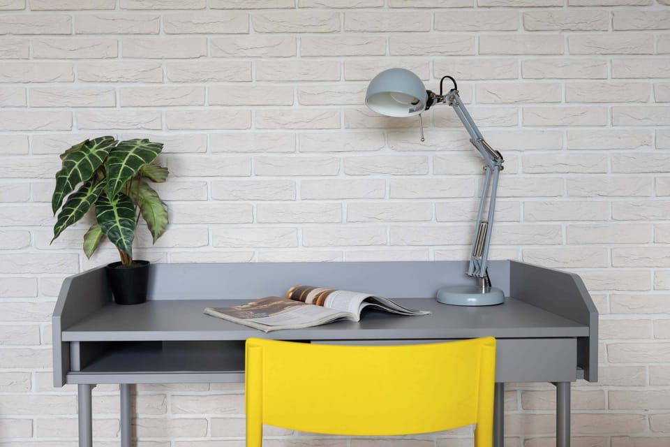 A comfortable grey desk with a yellow chair provides a comfortable place to work or study on the computer.