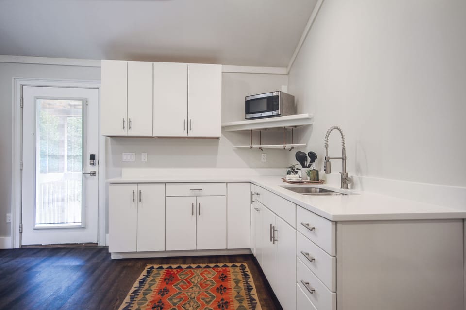 The Kitchenette with quartz countertop, microwave, hot plate, toaster, dishes.