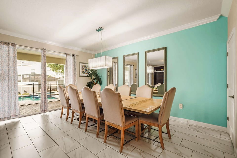 Private dining room with seating for ten, a statement pendant light, and views of the sparkling pool through the glass doors.