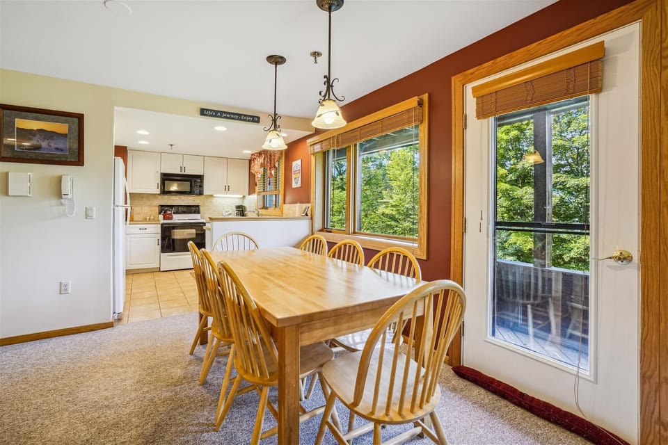 Large dining table with seating for the group, surrounded by natural light and wooded views.