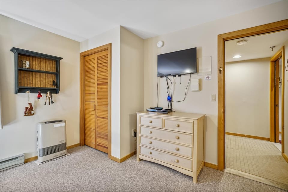 Comfortable bunk bedroom featuring a mounted TV, dresser storage, and space for additional guests.