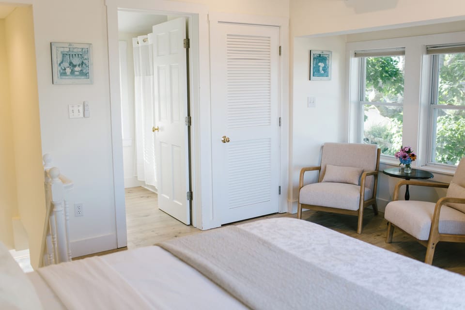 Relax in the sunlit sitting area of Room 8 at the Greenleaf Inn in Boothbay Harbor, Maine. This inviting corner features plush armchairs, garden views, and charming coastal decor—perfect for unwinding after a day by the sea.