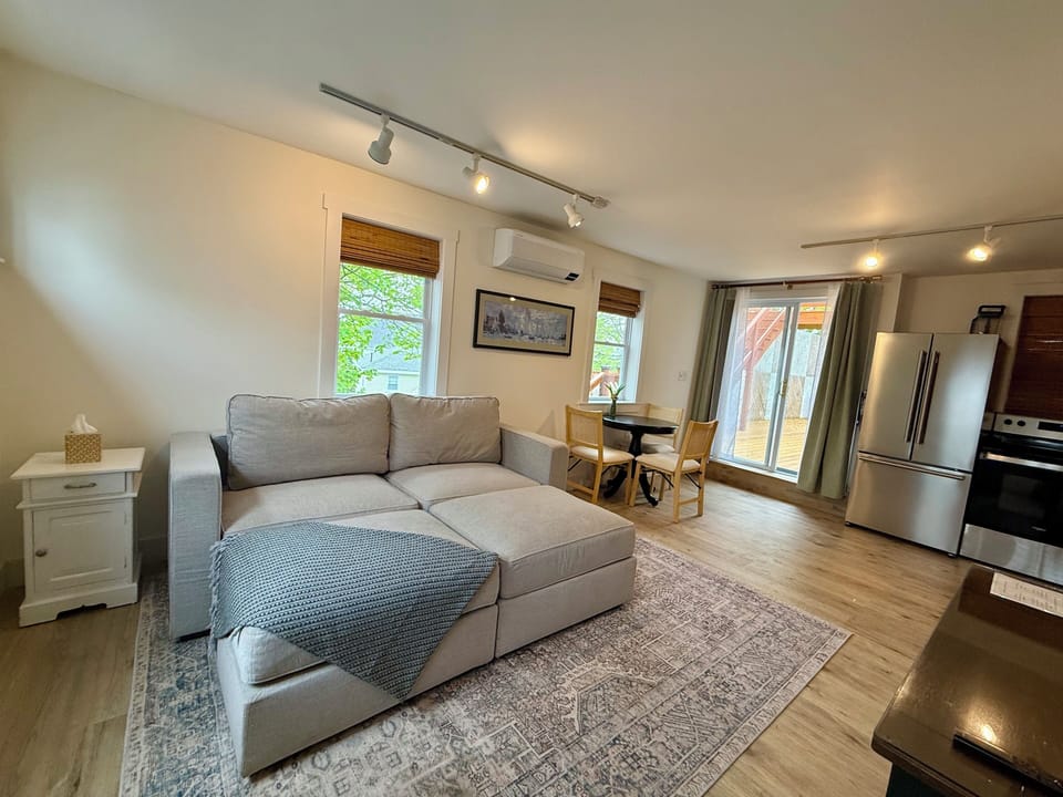 The lower level of Room 8 at the Greenleaf Inn features a cozy living space with a plush sectional, dining nook, and full kitchen. Thoughtfully designed for comfort and convenience—ideal for extended stays or relaxing between Boothbay adventures.