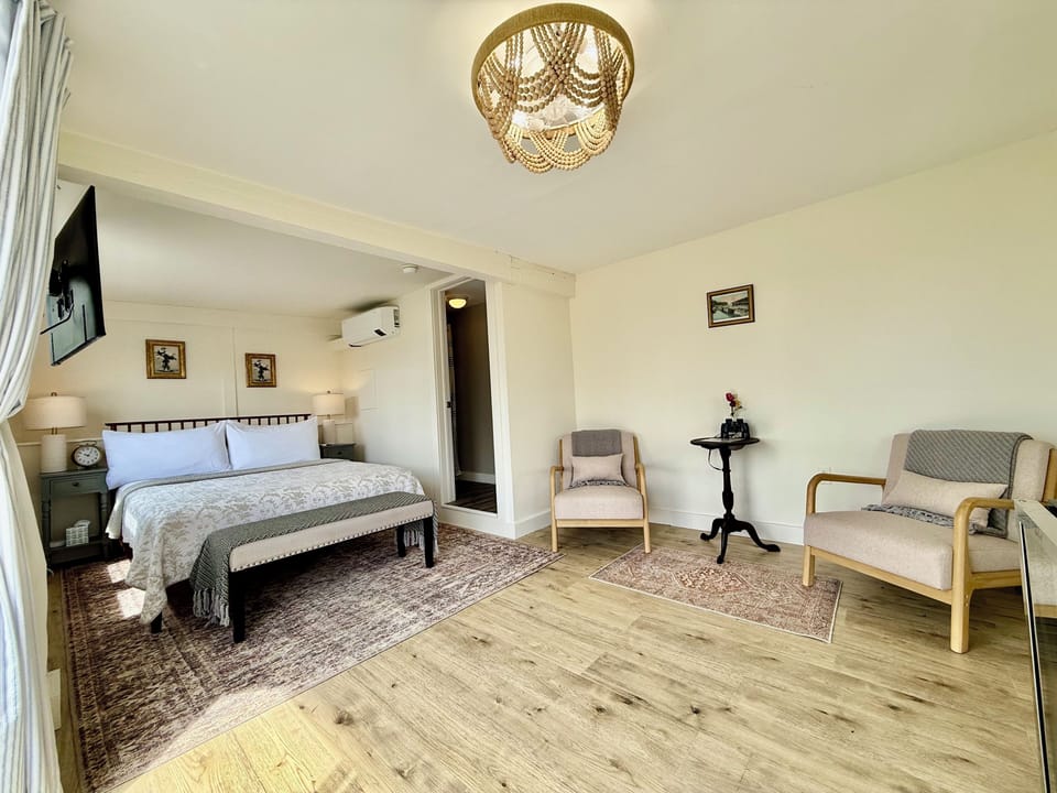 Room 9 offers a spacious layout with a plush king bed, cozy sitting area, hardwood floors, and elegant coastal décor. Enjoy comfort and charm just steps from the harbor at the Admiral's Quarters Inn in Boothbay Harbor, Maine.