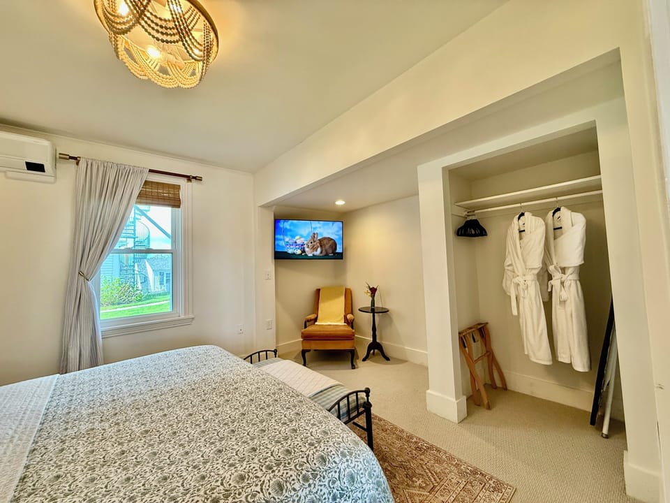 Room 10 at Admiral's Quarters Inn offers a serene retreat with soft linens, spa-style robes, a flat-screen TV, and views of the gardens—perfect for a relaxing Boothbay Harbor escape.