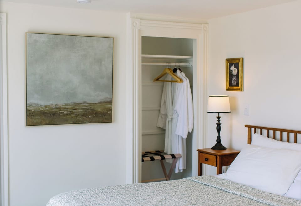 This tranquil corner of Admiral's Quarters Inn features soft bedding, cozy robes, elegant lighting, and curated artwork—perfect for a restful Boothbay Harbor escape.