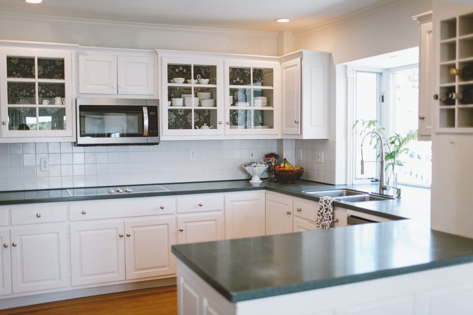 This spacious guest-use kitchen at Admiral's Quarters Inn features bright white cabinetry, modern appliances, and a welcoming layout—perfect for preparing snacks or meals during your relaxing coastal stay in Boothbay Harbor, Maine.
