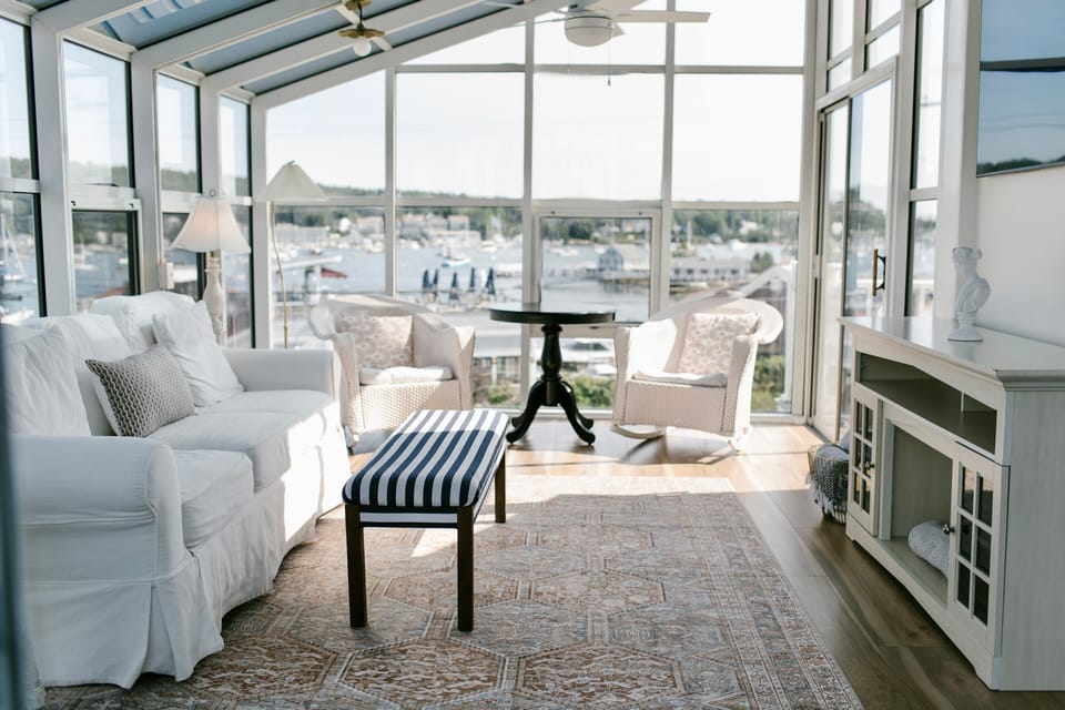 Relax in the bright, glass-enclosed solarium at Admiral's Quarters Inn. With plush seating, timeless décor, and panoramic harbor views, it's the perfect space to unwind, read, or sip coffee in classic Boothbay Harbor style.