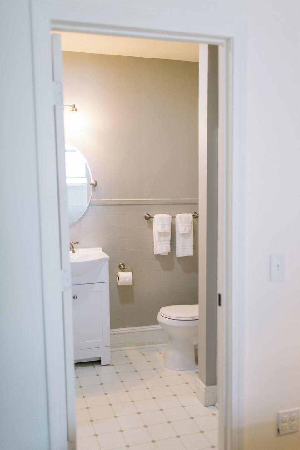 Room 13 includes a clean and comfortable private bathroom with a vanity, full mirror, and fresh towels—offering everything you need for a refreshing Boothbay Harbor stay.
