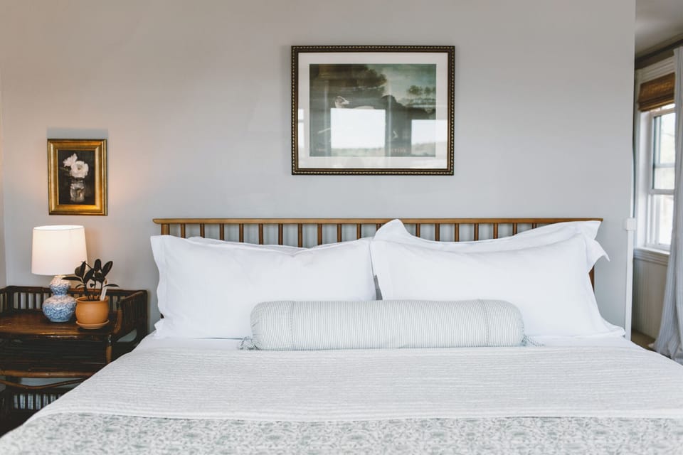 Room 15 features a plush king bed with crisp linens, serene artwork, and natural light—offering a peaceful, stylish retreat in the heart of Boothbay Harbor.