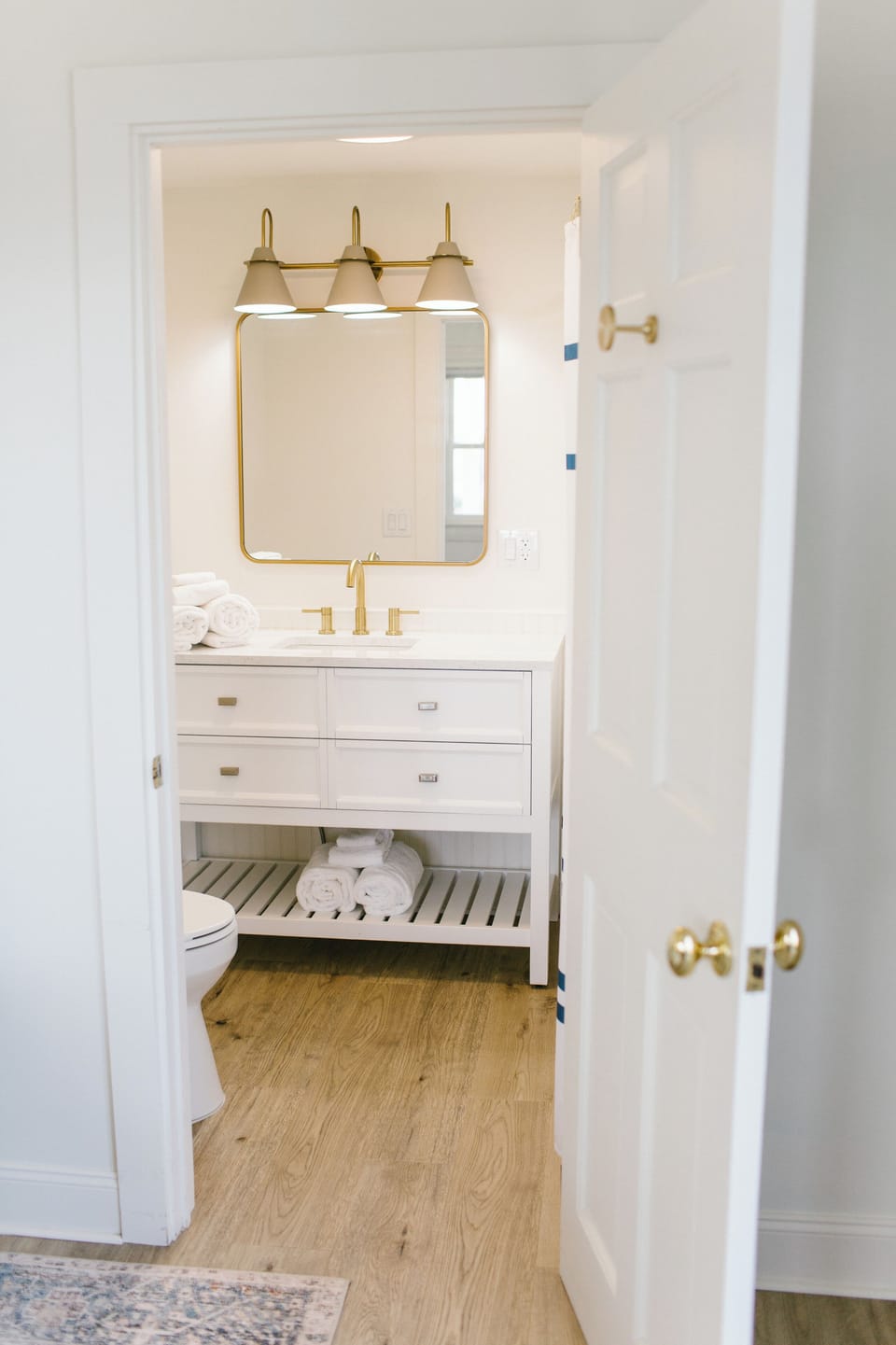 Enjoy a bright, modern ensuite bathroom featuring brass fixtures, fresh towels, and a spacious vanity. Clean, comfortable, and thoughtfully designed—perfect for relaxing after a day exploring the charm of Boothbay Harbor.