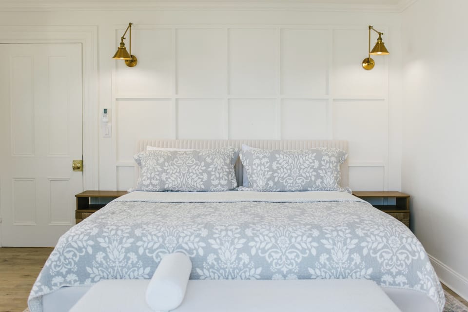 Relax in a serene, stylish king room featuring designer bedding, modern brass lighting, and classic coastal charm. Perfect for a restful night after exploring the scenic shops, restaurants, and harbor views of Boothbay.