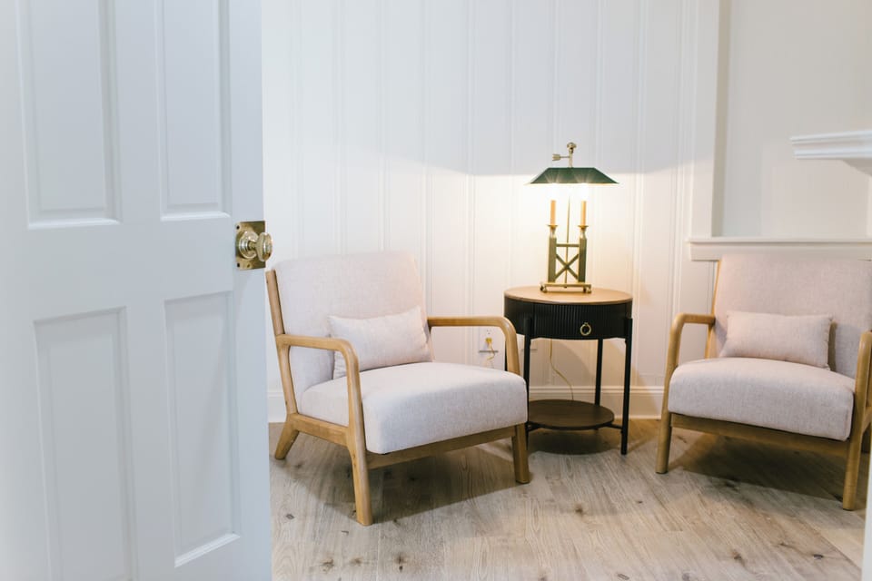 Unwind in Room 2's peaceful sitting area, featuring two plush armchairs, warm lighting, and timeless charm. A perfect spot to relax during your Boothbay Harbor stay at the Greenleaf Inn.